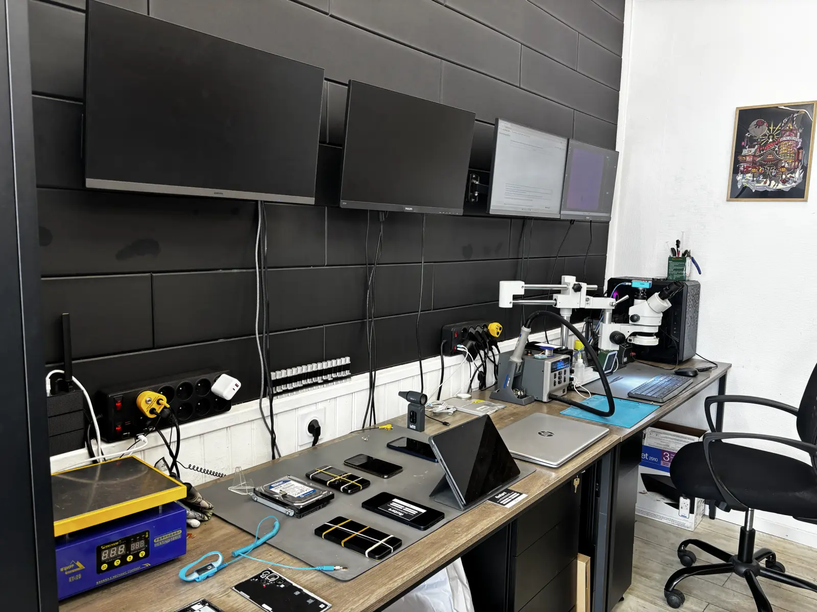 Poste technique de Fixstore avec écrans, appareils en réparation et microscope de microsoudure